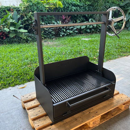 Black BBQ grill on a wooden pallet outdoors with greenery in the background