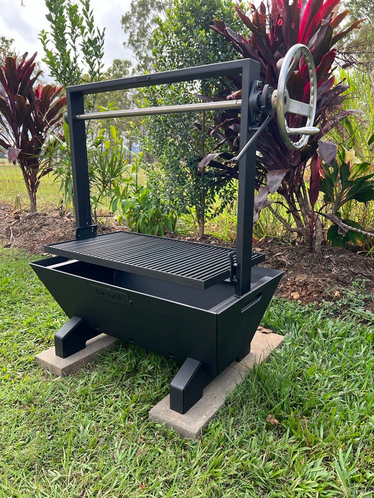 Black barbecue fire pit grill on a grassy area with plants in the background