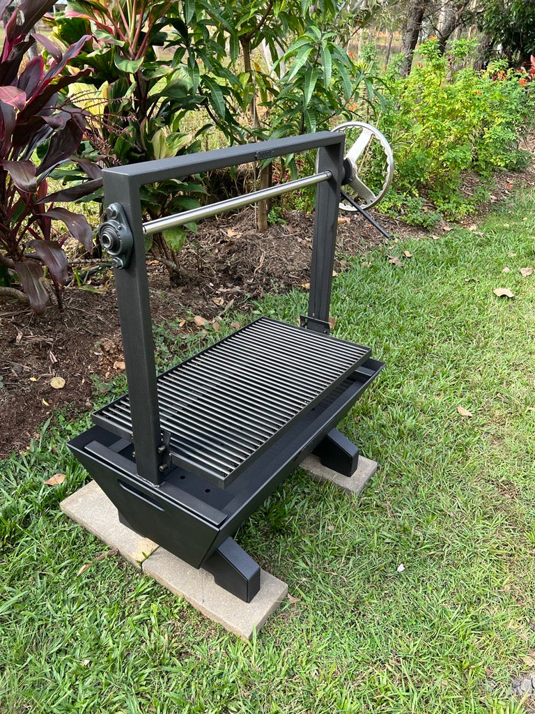 Black Santa maria parrilla asaso barbecue grill on a concrete block outdoors with greenery in the background