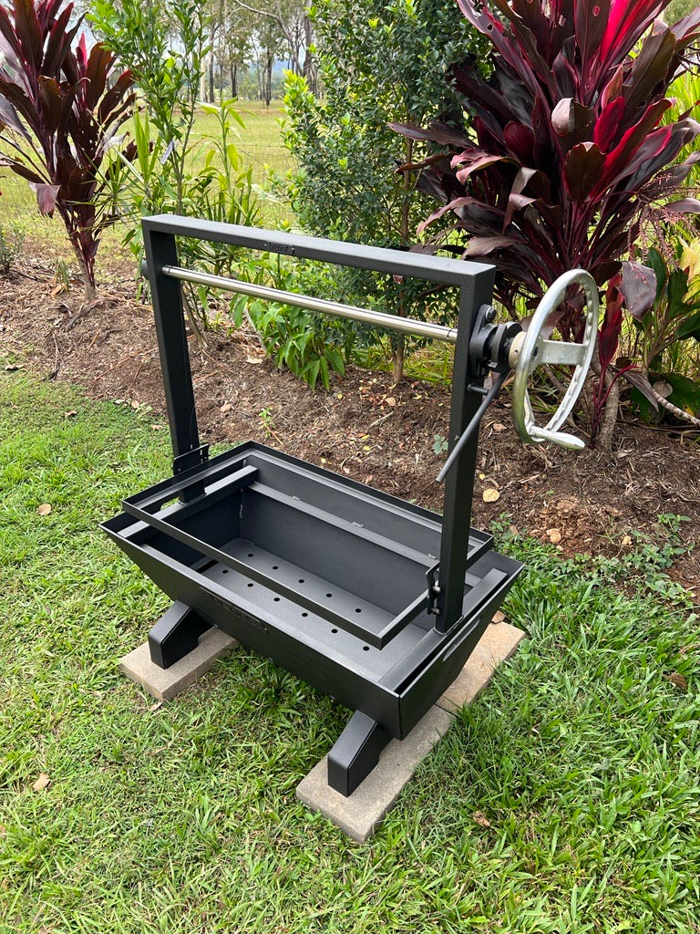 Black Santa maria parrilla asado barbecue grill on a concrete block outdoors with greenery in the background