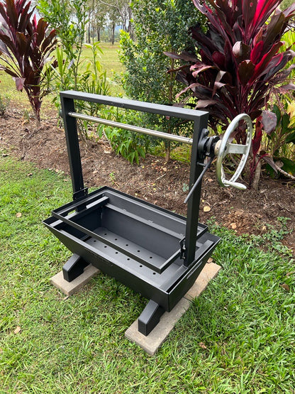 Black Santa maria parrilla asado barbecue grill on a concrete block outdoors with greenery in the background