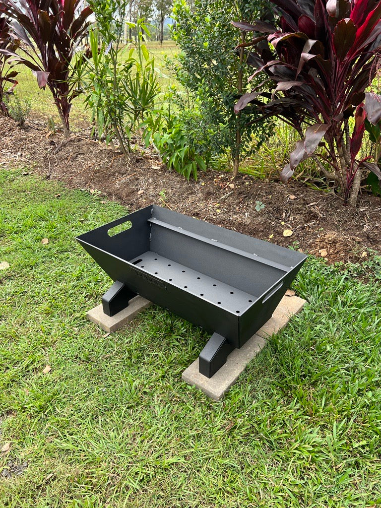 Black Santa maria parrilla asado barbecue grill on a concrete block outdoors with greenery in the background