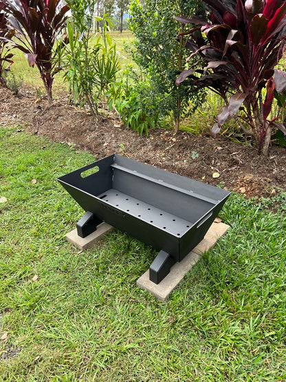Black Santa maria parrilla asado barbecue grill on a concrete block outdoors with greenery in the background
