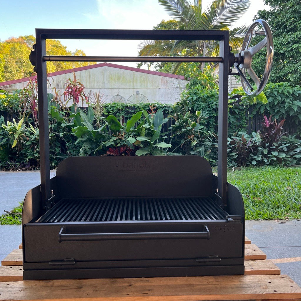 Black BBQ grill on a wooden platform with a garden background